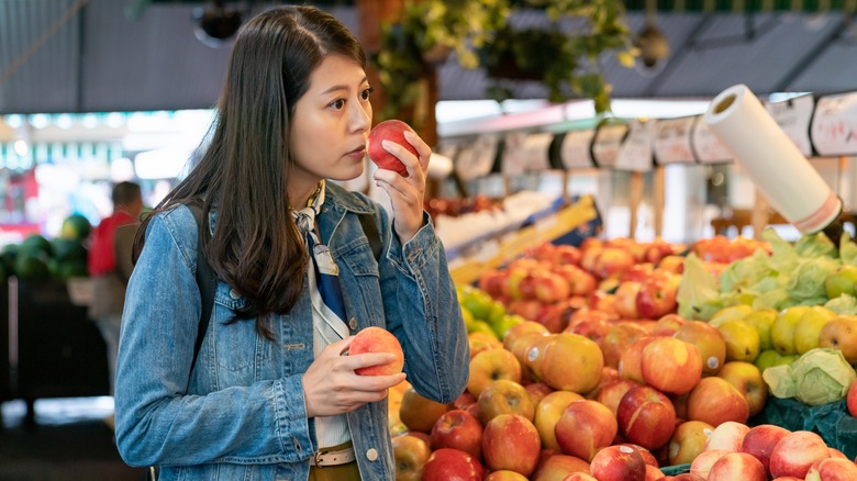 woman smelling peach at store