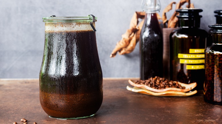 Cold brew coffee steeping in a jar with coffee grounds