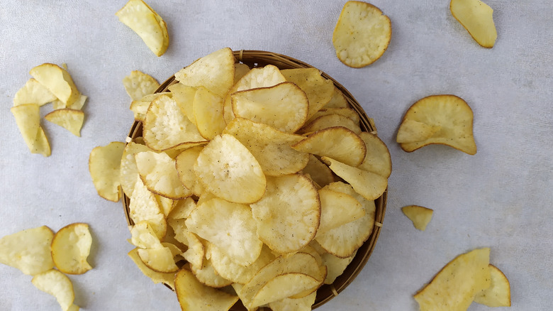 Potato chips are overflowing from a bowl in this aerial view.