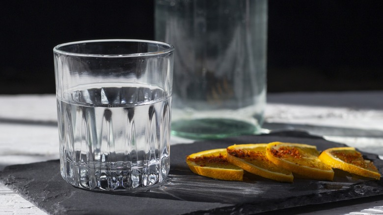 A glass half full of blanco tequila placed on a table.