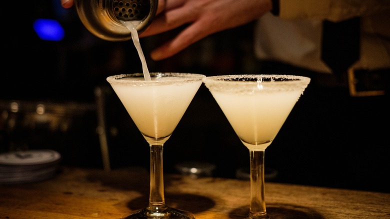 A bartender pouring two margaritas.