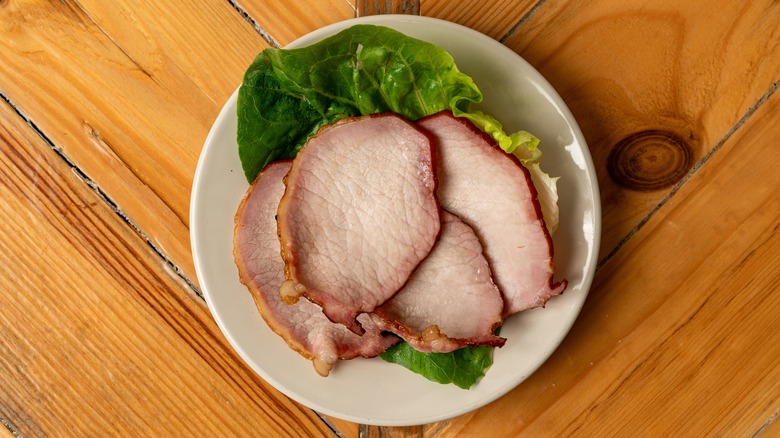 cooked Canadian bacon on lettuce