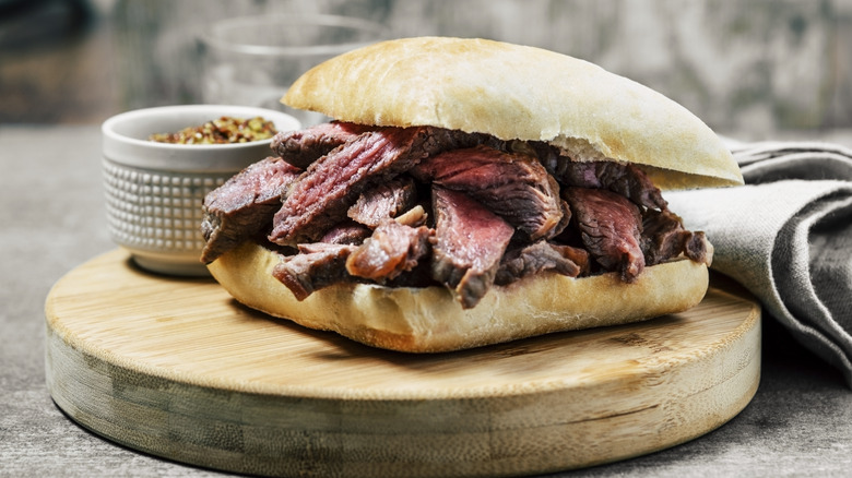 A huge grilled steak sandwich is piled with meat.