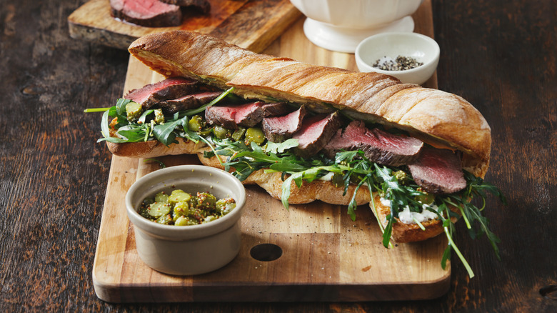 A beautiful steak sandwich lined with rosy beef slices.