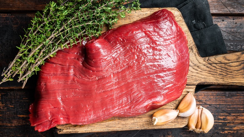 A raw cut of flank steak on a cutting board clearly showing its grain structure