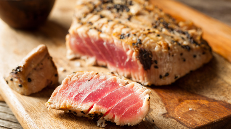 Seared rare to medium-rare tuna on cutting board.