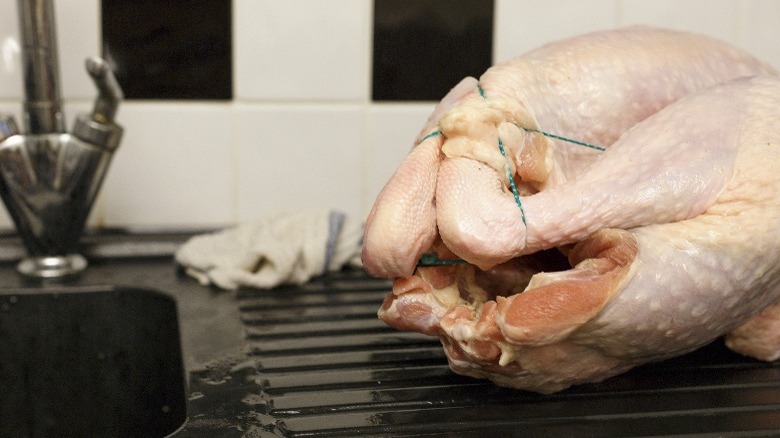 Thawed turkey beside the sink is prepped for cooking