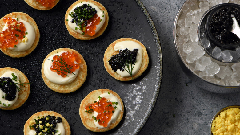 Caviar on blini from above with plates and on ice