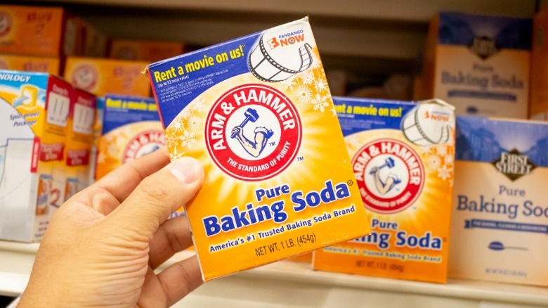 Hand grabbing baking soda off of a shelf