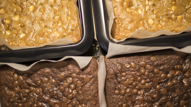 Parchment paper-lined pans of brownies and blondies