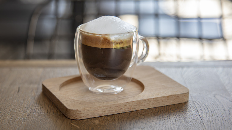 A macchiato on a wooden platter.