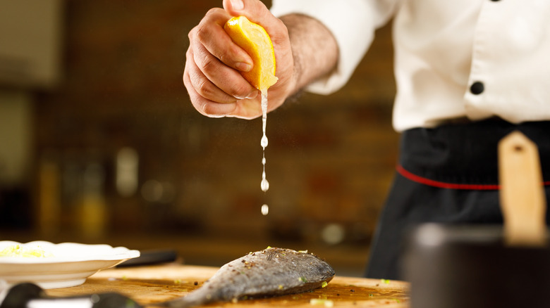 Person squeezing fresh lemon over fish