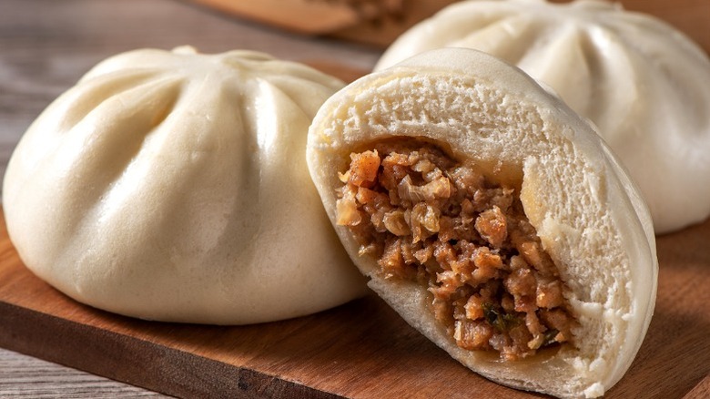 Char siu bao buns. One is cut in half with filling coming out.