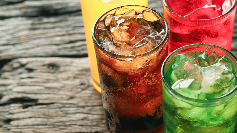 four glasses of various soft drinks