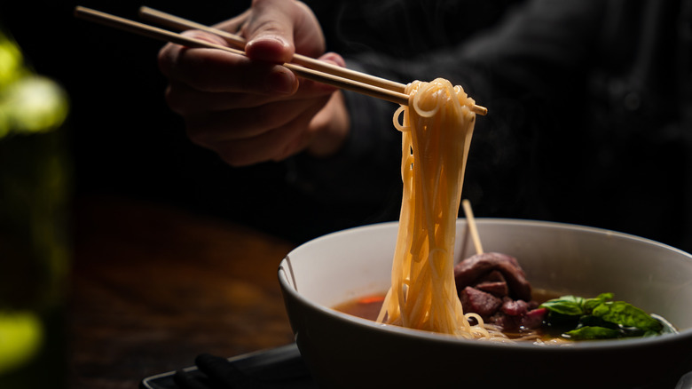 Person eating ramen with chopsticks