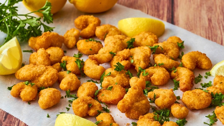 Popcorn shrimp, lemons, and parsley on parchment paper