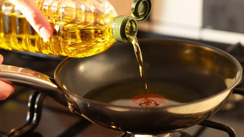 Person adding oil to a skillet