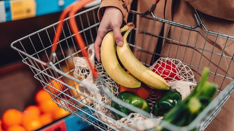 Person putting bananas in shopping basket