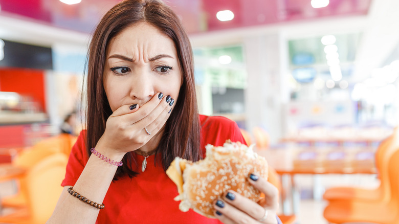 Woman grossed out hand mouth burger