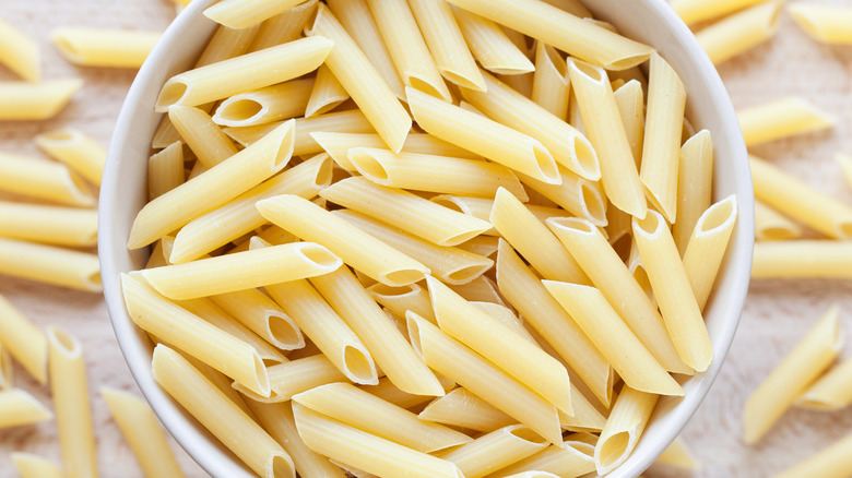 A bowl of dried penne on a counter