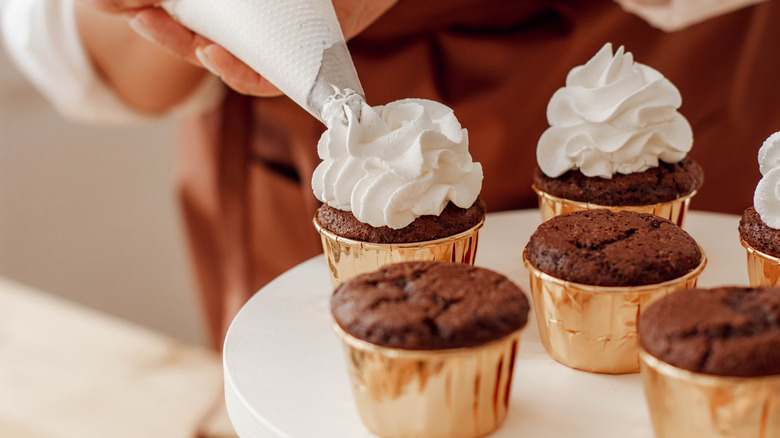 Cupcakes are frosted from a pastry bag.