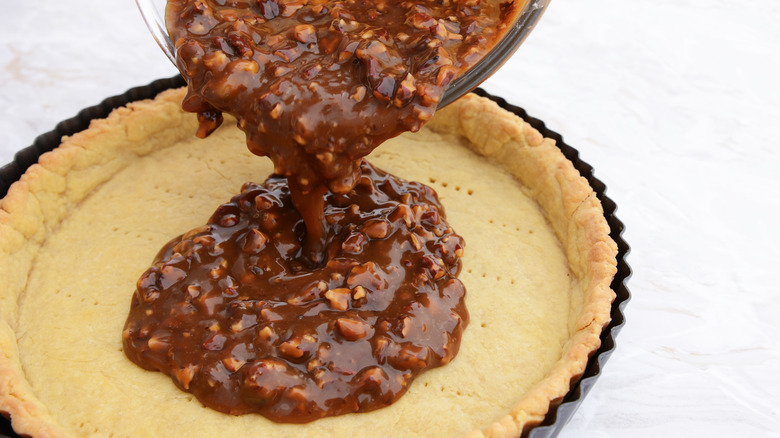 Pouring pecan pie filling into pie shell