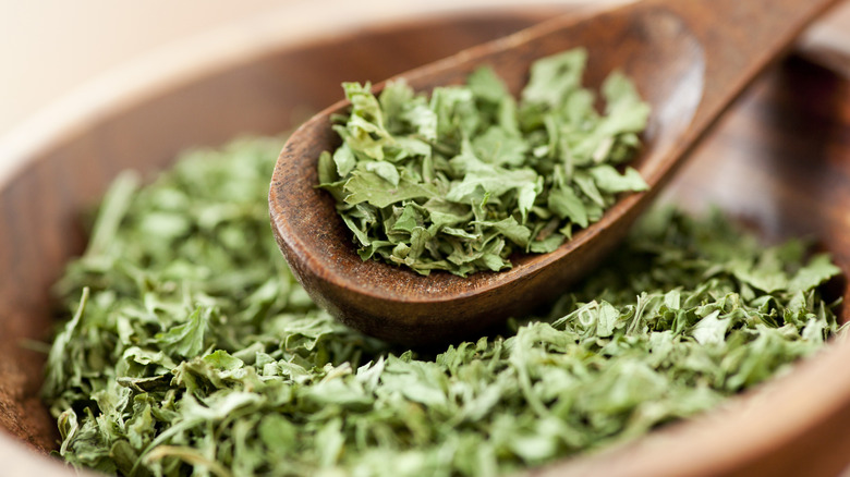 Wooden spoon and bowl of dried parsley