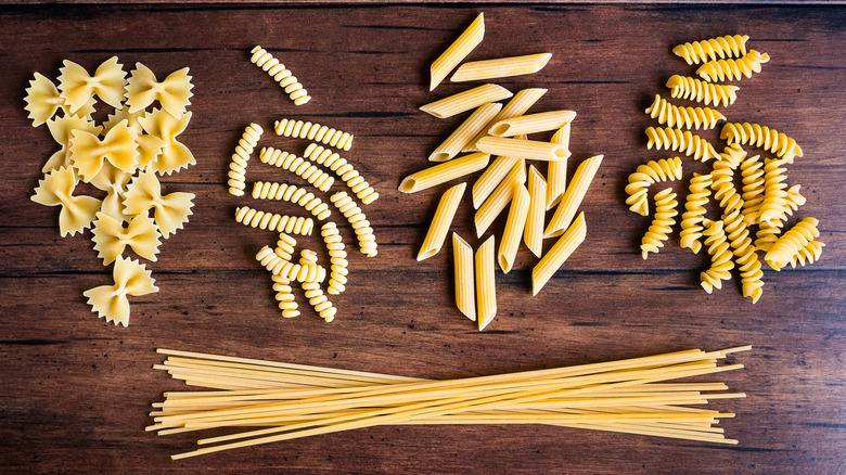 Assorted dried pasta on wood background