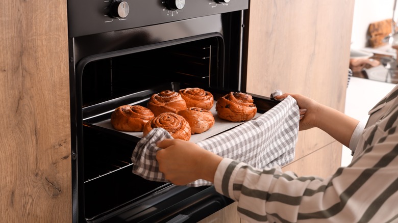 A woman takes pastries out of the oven