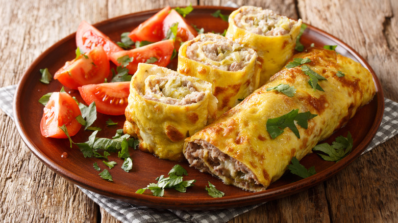 Soft omelet egg roll on a brown plate with tomatoes