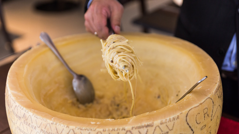 pasta rolled up and served from a cheese wheel 