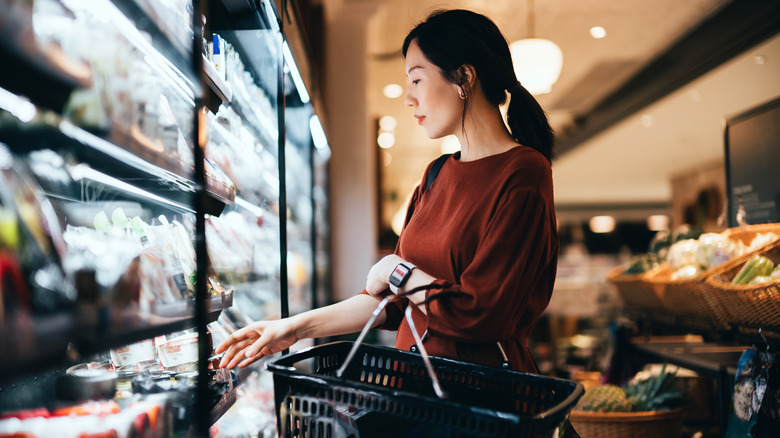 Woman holds a shopping basket in grocery store