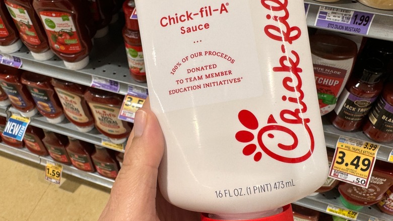 A shopper holds a bottle of Chick-fil-A sauce in the aisle