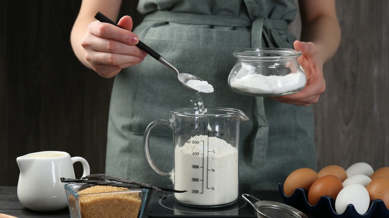 hands measuring flour in a cup