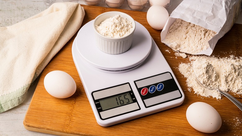 digital food scale on cutting board with flour