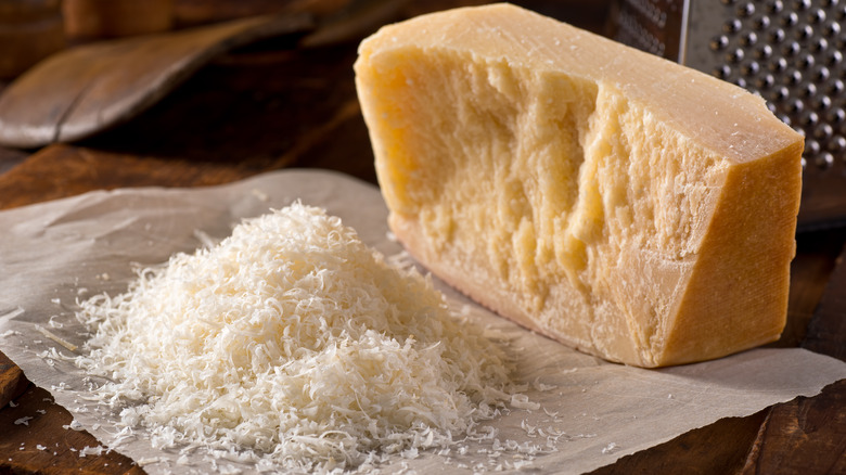 A block of parmesan next to a pile of grated parmesan