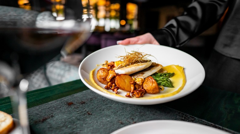 Server presenting a fish entree at an upscale restaurant