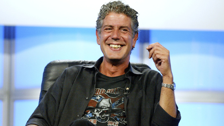 Anthony Bourdain smiles while sitting on stage