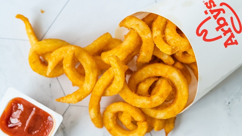 Arby's curly fries cast on a table with a ketchup packet