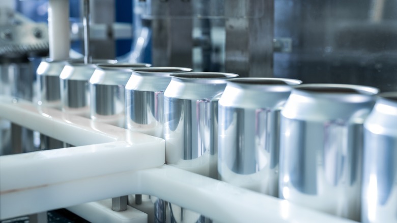 New aluminum cans moving through a production line in a factory