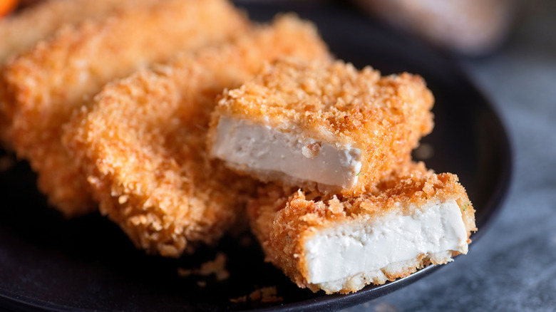 A plate of crispy tofu rests on a table