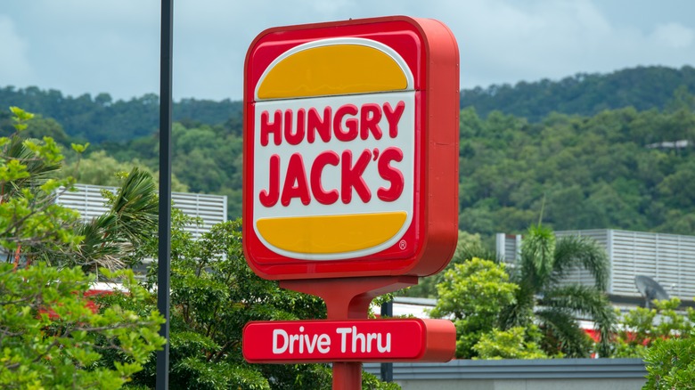 Red hungry jack's sign above trees. 