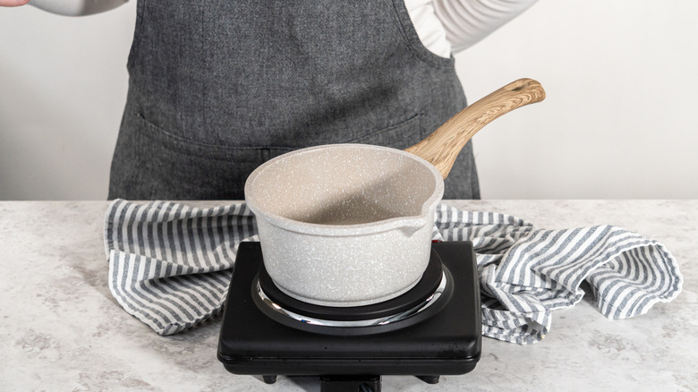 Simple syrup is prepared in a small white pot on a hot plate.