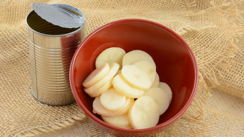 sliced canned potatoes in red bowl with open can