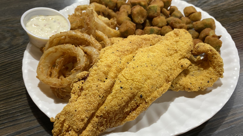 Fried catfish on a plate with onion rings and fried okra