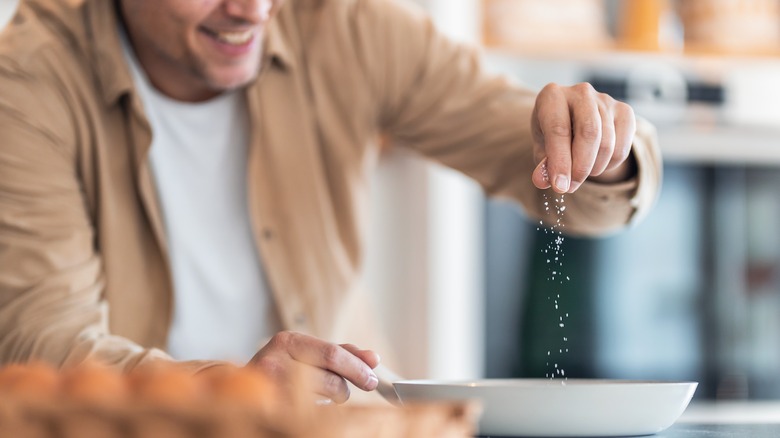 man sprinkling salt onto food