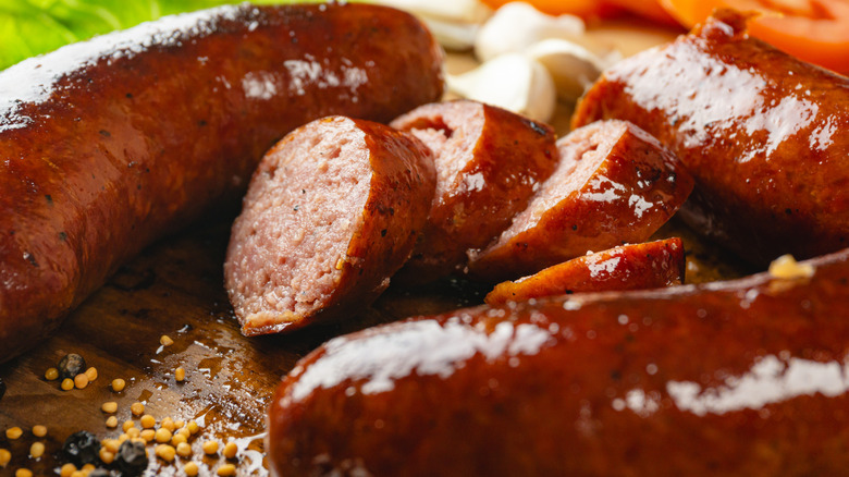 Sliced cooked sausage sitting on a wooden cutting board