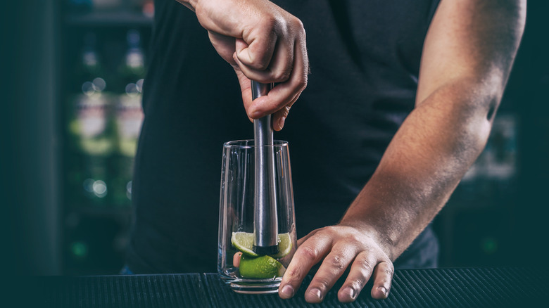 Bartending crushing lime in glass