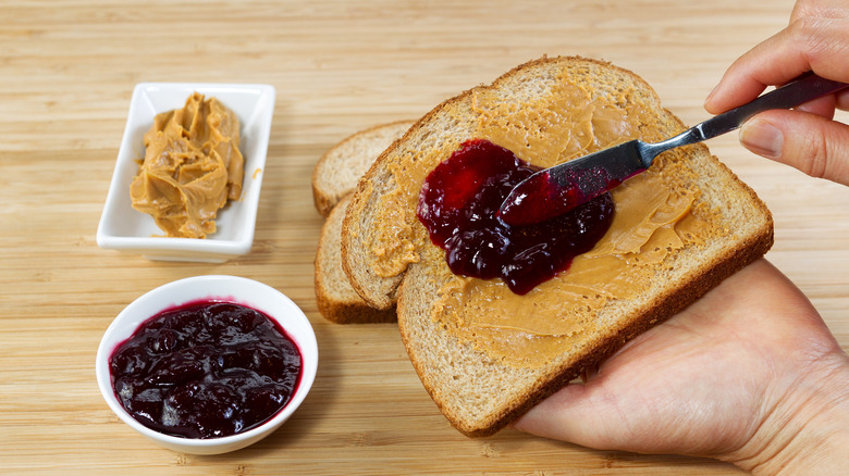 Hands spreading jelly on bread with knife