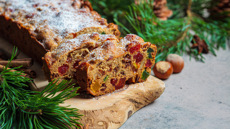 a loaf of fruitcake sliced up next to pine boughs